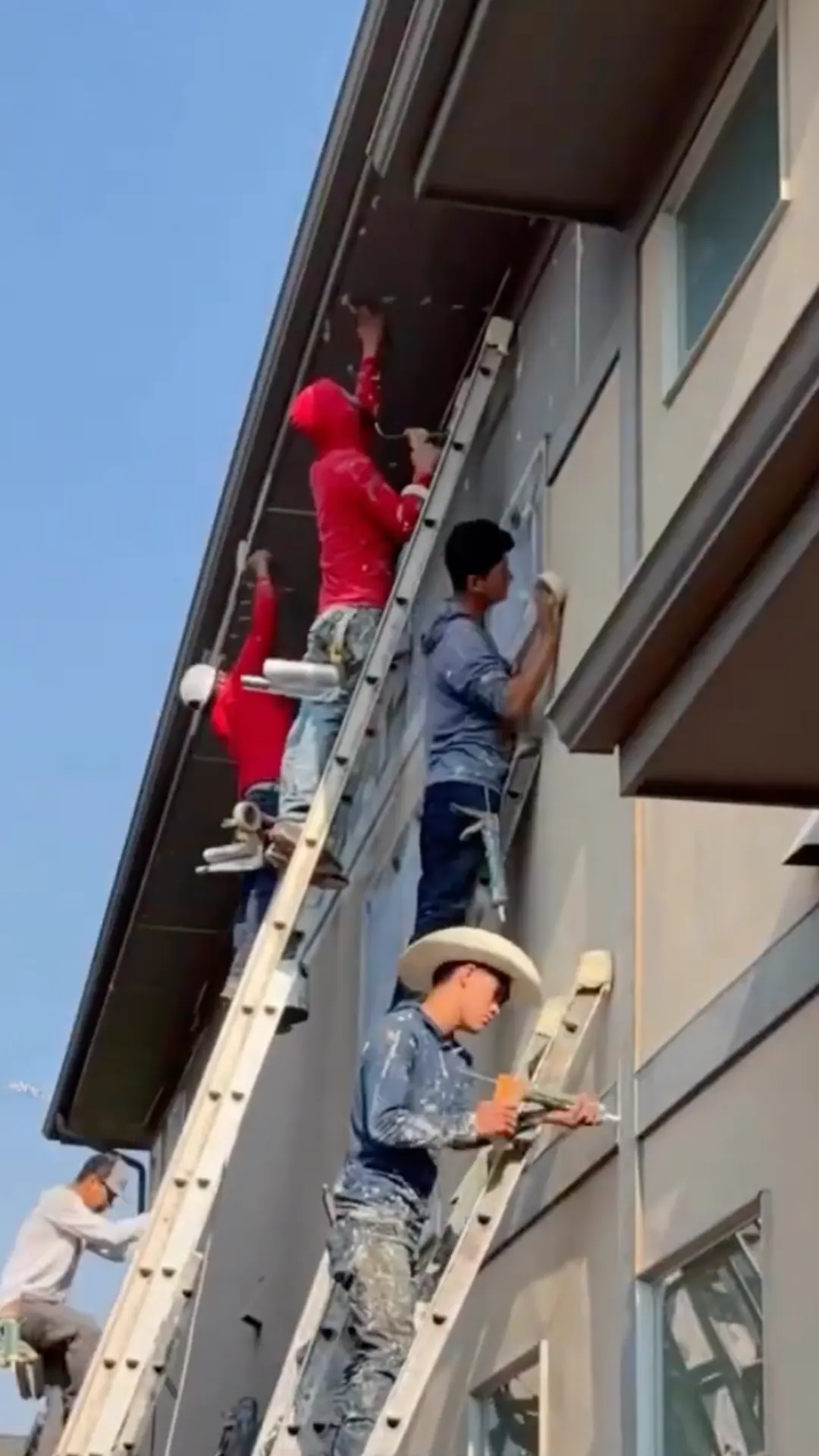 Kind Home Painting crew on ladders prepping and caulking the second story of a north Denver home before exterior painting