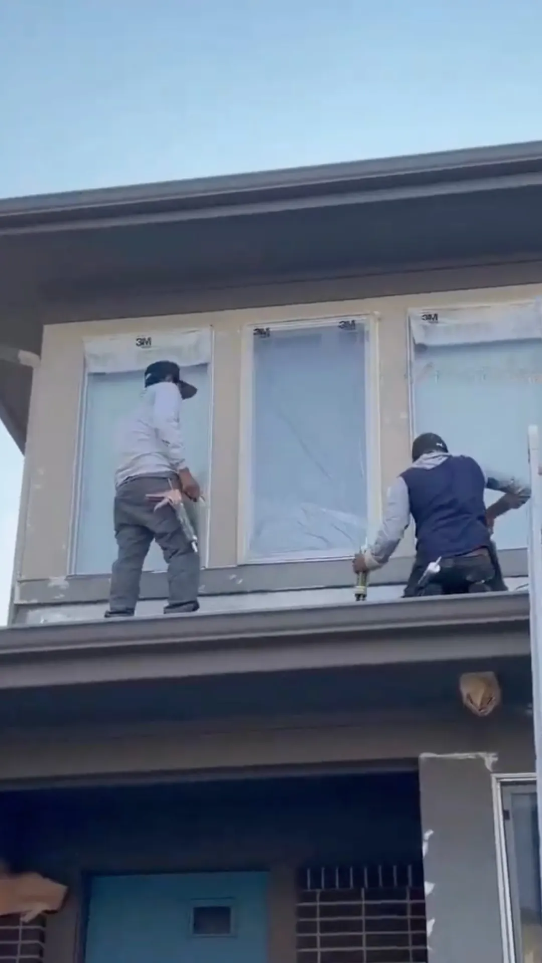 Two Kind Home painters masking and caulking upper-story windows during exterior paint prep in Denver